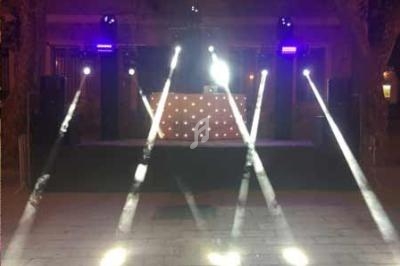 Jeux de lumières colorées projetés sur une scène extérieure avec une table de mixage en arrière-plan.