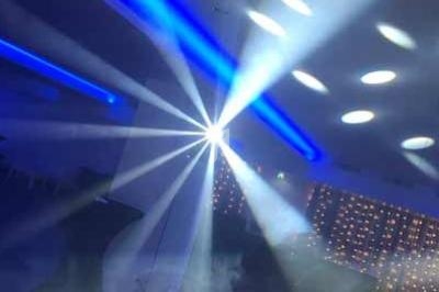 Effets lumineux colorés et fumée dans une salle sombre, créant une ambiance festive.