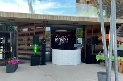 Façade d'un bâtiment avec une installation de DJ comprenant une table blanche, des enceintes et des éclairages.