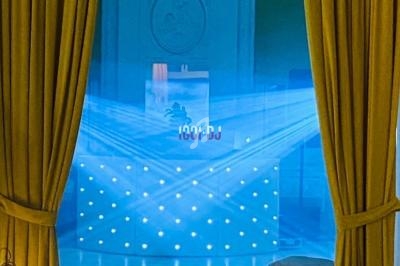 Vue d'une piste de danse éclairée par des faisceaux lumineux bleus, encadrée par des rideaux jaunes.