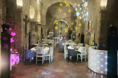 Salle voûtée en pierre avec tables dressées, éclairage tamisé et projections lumineuses en forme d'étoiles.