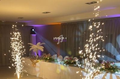 Salle décorée pour un événement avec une table ornée de fleurs et des fontaines lumineuses en fonctionnement.