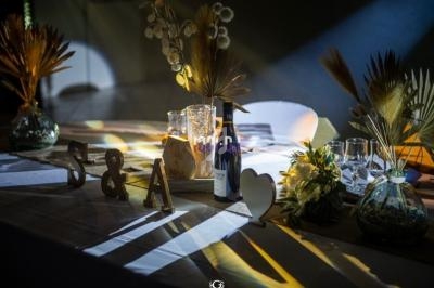Table décorée pour un événement avec vases, fleurs séchées, bougies, initiales en bois et lumière tamisée.