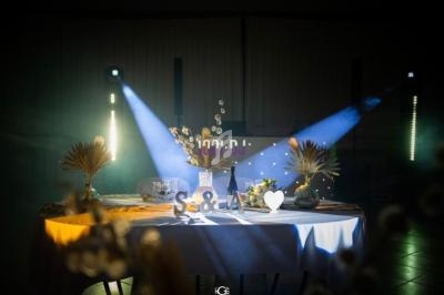 Table décorée avec des fleurs séchées, des lettres ’S & A’ et un éclairage coloré dans une ambiance tamisée.