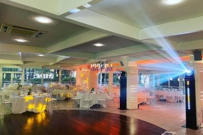 Salle de réception lumineuse avec tables dressées, chaises transparentes et éclairage décoratif.