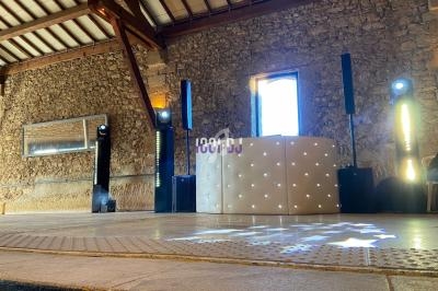 Installation de matériel de sonorisation et éclairage dans une salle en pierre avec un pupitre lumineux.