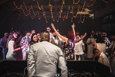 Un DJ anime une soirée dansante avec des invités qui dansent sous des lumières suspendues.