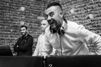 Un homme souriant avec un casque audio autour du cou, devant deux autres hommes, dans un cadre en pierre.