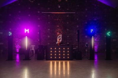 Installation lumineuse avec des projecteurs colorés et une table de mixage dans une salle sombre en pierre.