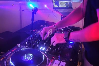 Un DJ mixant de la musique sur une console Pioneer avec un ordinateur portable en arrière-plan.