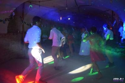 Des personnes dansent sous des lumières colorées dans une ambiance festive et tamisée.