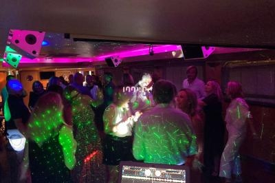 Groupe de personnes dansant dans une salle éclairée par des lumières colorées et des effets laser.