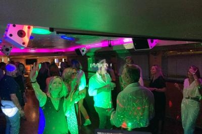 Des personnes dansent et discutent sous des lumières colorées dans une ambiance festive en intérieur.