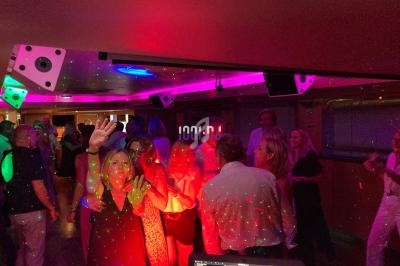 Des personnes dansent sous des lumières colorées dans une salle animée avec une ambiance festive.