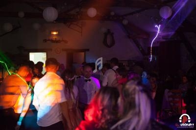 Groupe de personnes dans une salle sombre avec éclairages colorés, ambiance festive et musique.