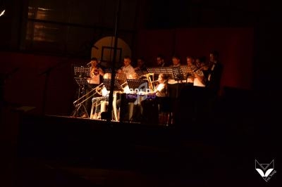 Un groupe de musiciens joue sur scène dans une salle sombre, éclairée par des projecteurs.