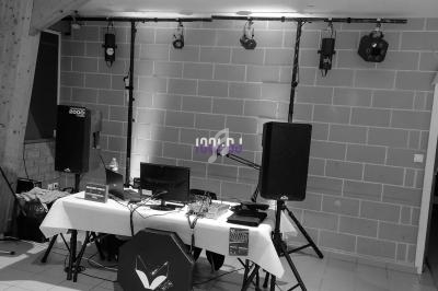 Matériel de sonorisation installé dans une salle, comprenant enceintes, table de mixage et éclairages suspendus.