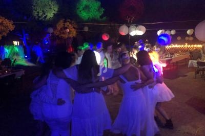 Groupe de personnes en cercle dansant sous des lumières colorées lors d'une fête en plein air.