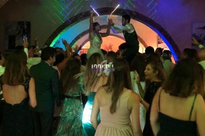 Personnes dansant sous des jeux de lumière colorés dans une salle festive avec une arche en arrière-plan.