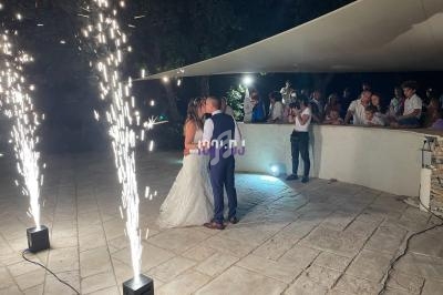 Un couple danse sous des étincelles lors d'une réception en extérieur, entouré d'invités.