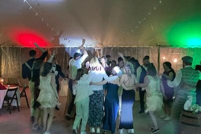 Des personnes dansent sous une tente éclairée de lumières colorées, créant une ambiance festive.