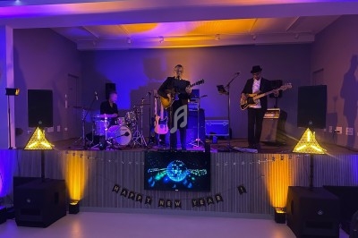 Un groupe de musiciens joue sur une scène éclairée, avec des décorations de Nouvel An en arrière-plan.