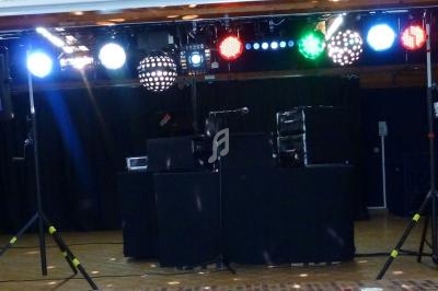 Installation de matériel de sonorisation et d'éclairage sur une scène, avec projecteurs colorés et enceintes.