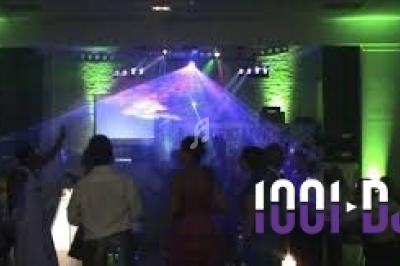 Groupe de personnes dansant sous des lumières colorées et des effets laser dans une salle sombre.