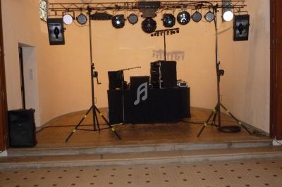 Installation de matériel audio et éclairage sur une scène intérieure avec projecteurs et enceintes.