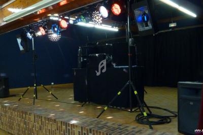 Installation de matériel de sonorisation et d'éclairage sur une scène en intérieur, prête pour un événement.
