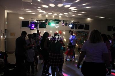 Des personnes dansent dans une salle éclairée par des lumières colorées lors d'une soirée festive.