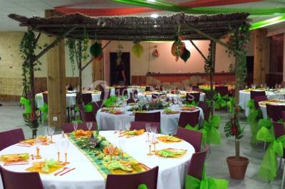 Salle de réception décorée avec des tables alignées, nappes grises, serviettes bleues et chaises rouges.