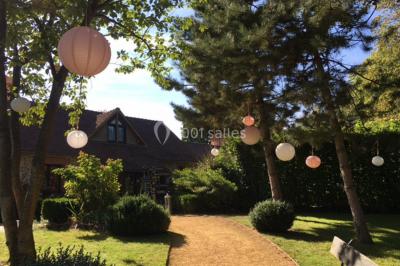Décoration festive sous une tente avec arche lumineuse, sapins de Noël, guirlandes et sol en bois.