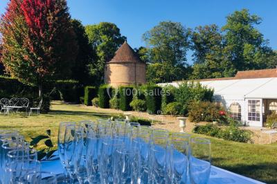 Décoration festive sous une tente avec arche lumineuse, sapins de Noël, guirlandes et sol en bois.