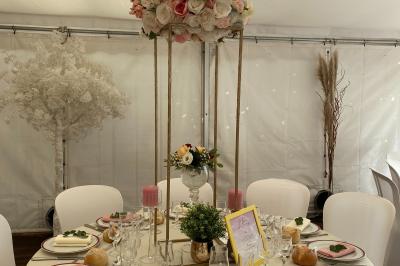 Décoration festive sous une tente avec arche lumineuse, sapins de Noël, guirlandes et sol en bois.