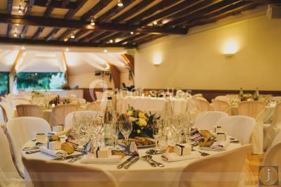 Décoration festive sous une tente avec arche lumineuse, sapins de Noël, guirlandes et sol en bois.