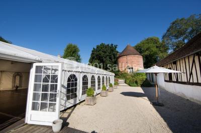 Décoration festive sous une tente avec arche lumineuse, sapins de Noël, guirlandes et sol en bois.