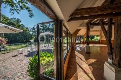 Décoration festive sous une tente avec arche lumineuse, sapins de Noël, guirlandes et sol en bois.