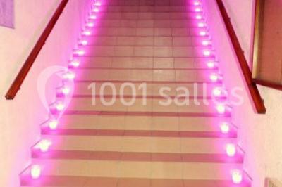 Chambre mansardée avec un lit double blanc, parquet au sol, mur beige et lumière naturelle provenant d'une porte-fenêtre.