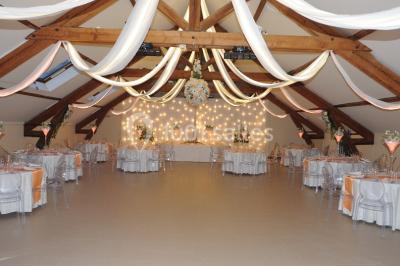 Chambre mansardée avec un lit double blanc, parquet au sol, mur beige et lumière naturelle provenant d'une porte-fenêtre.
