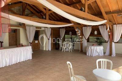 Chambre mansardée avec un lit double blanc, parquet au sol, mur beige et lumière naturelle provenant d'une porte-fenêtre.