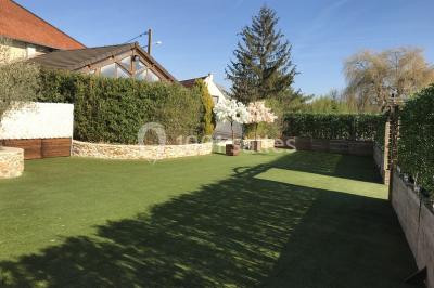 Chambre mansardée avec un lit double blanc, parquet au sol, mur beige et lumière naturelle provenant d'une porte-fenêtre.