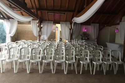 Chambre mansardée avec un lit double blanc, parquet au sol, mur beige et lumière naturelle provenant d'une porte-fenêtre.