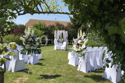 Chambre mansardée avec un lit double blanc, parquet au sol, mur beige et lumière naturelle provenant d'une porte-fenêtre.