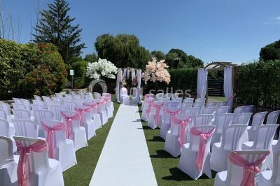Chambre mansardée avec un lit double blanc, parquet au sol, mur beige et lumière naturelle provenant d'une porte-fenêtre.