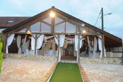 Chambre mansardée avec un lit double blanc, parquet au sol, mur beige et lumière naturelle provenant d'une porte-fenêtre.
