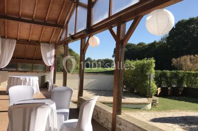 Chambre mansardée avec un lit double blanc, parquet au sol, mur beige et lumière naturelle provenant d'une porte-fenêtre.