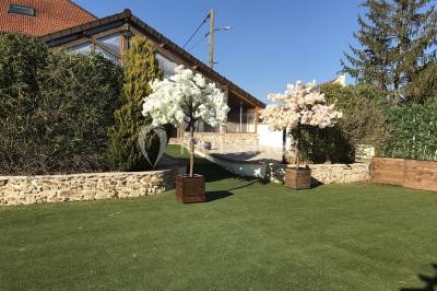Chambre mansardée avec un lit double blanc, parquet au sol, mur beige et lumière naturelle provenant d'une porte-fenêtre.