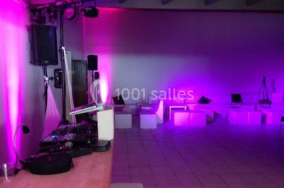 Salle de réception décorée avec des guirlandes lumineuses, des lanternes suspendues et des tables dressées pour un événement.