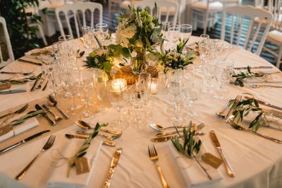 Salle de réception décorée avec des guirlandes lumineuses, des lanternes suspendues et des tables dressées pour un événement.